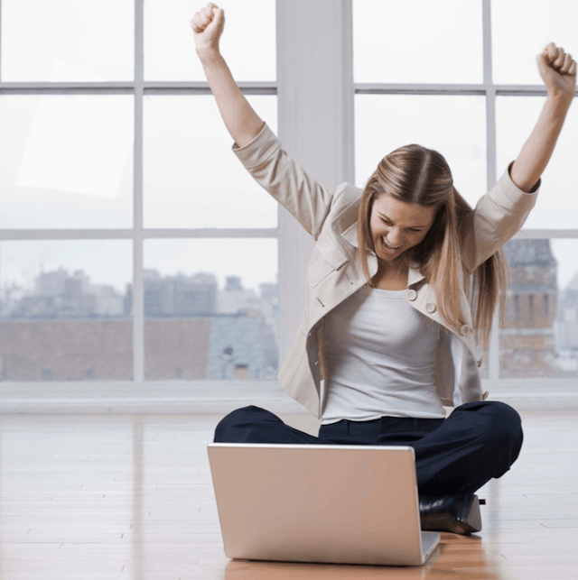 Worker celebrating while working on laptop
